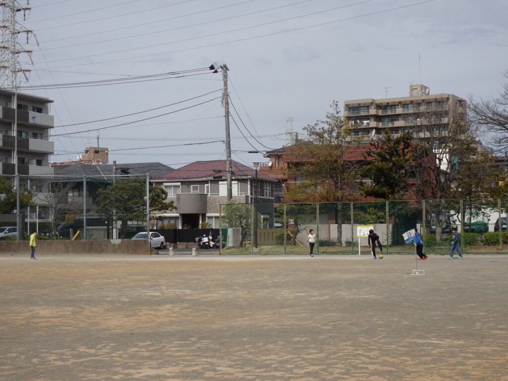 公園の広場エリアでサッカーを楽しむ児童